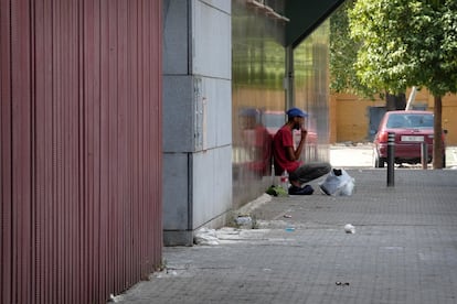 A young man sitting on the street next to the Litanías health center, in the Polígono Sur of Seville.