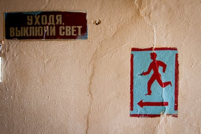 Next to a sign in Ukrainian asking to turn off the light when leaving, another marks the emergency exit to the shelter in case of bombing at a center for internally displaced people in Kharkiv, on August 2, 2024.