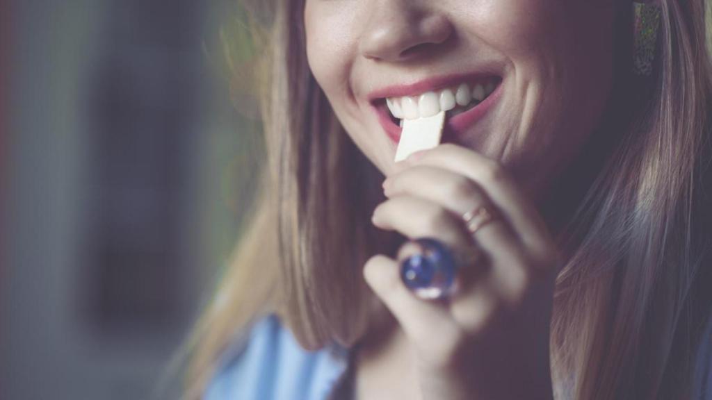 Woman putting a piece of gum in her mouth.